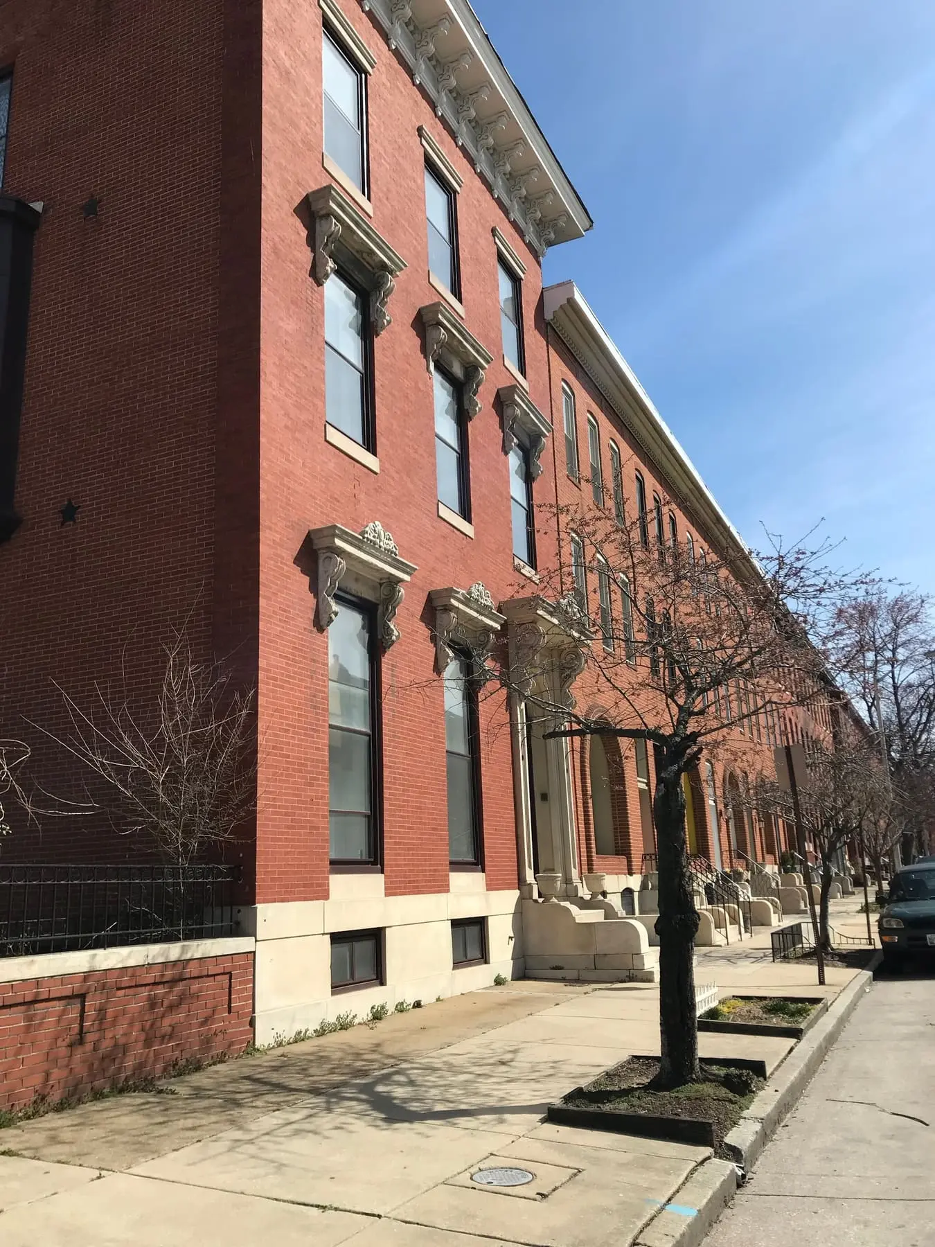 Alignement de rowhouses en brique typiques de l’est de Baltimore, corniches ouvragées et perrons de marbre