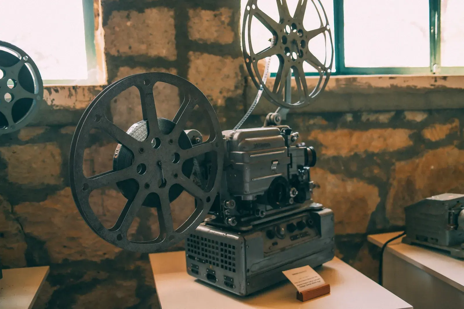 Projecteur de cinéma ancien et ses bobines, posé dans une pièce aux murs de pierre